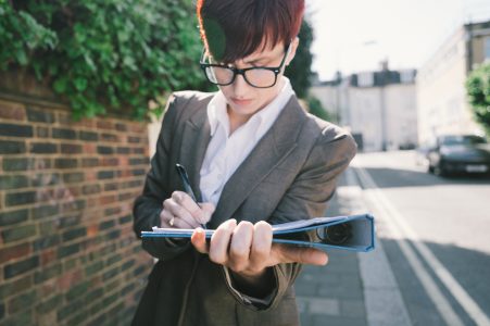 Female wearing grey blazer writing on a folder