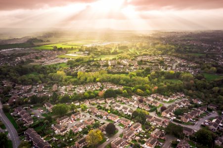 Sun bursting through clouds over houses in the countryside